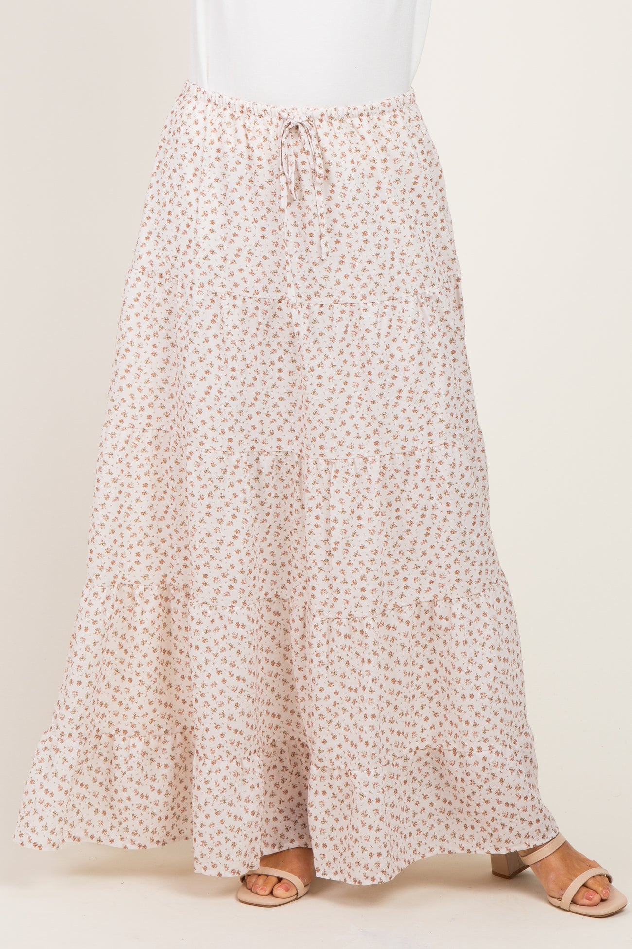 woman wearing a flowy beige floral maxi skirt with a drawstring waist and tiered design