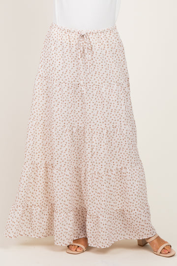 woman wearing a flowy beige floral maxi skirt with a drawstring waist and tiered design