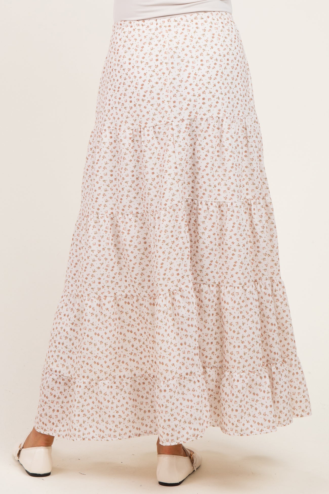 woman wearing a white floral print maternity maxi skirt with tiered design, seen from the back