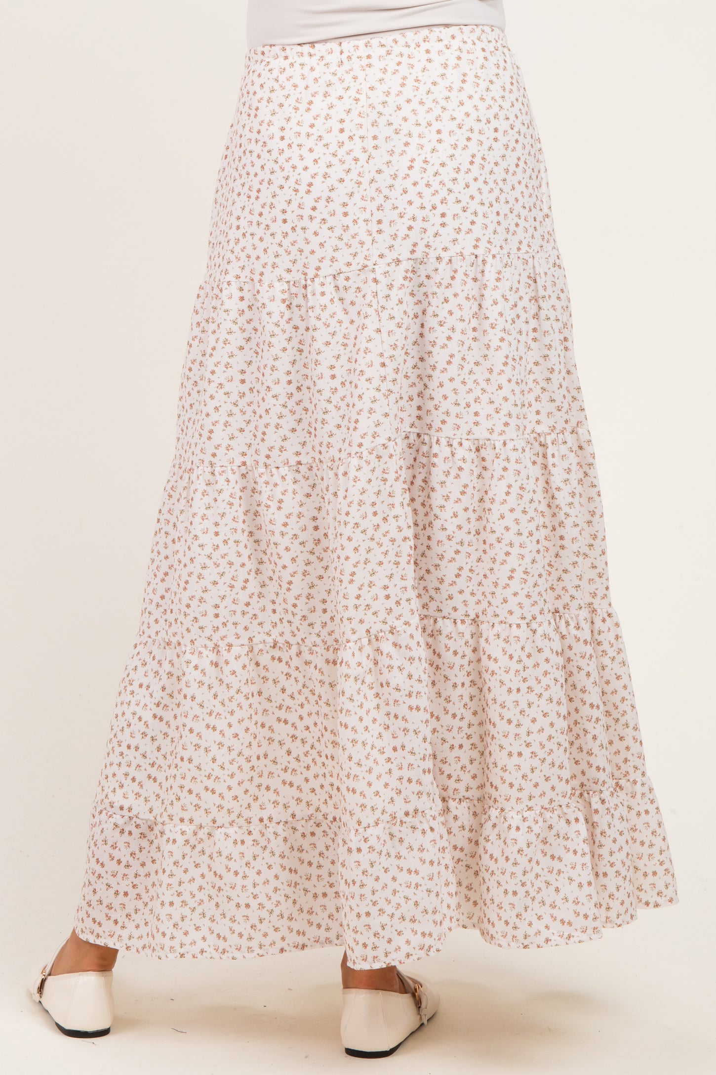woman wearing a white floral print maternity maxi skirt with tiered design, seen from the back