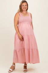 woman wearing a pink striped maternity plus maxi dress with a smocked bodice and tiered skirt, showing her baby bump