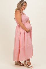 woman wearing a pink striped maternity maxi dress with a smocked bodice and holding her baby bump