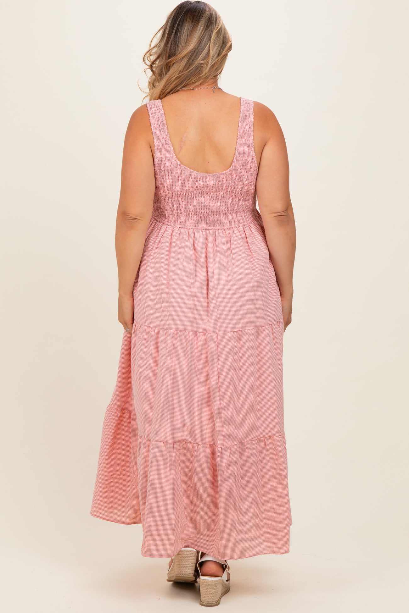 woman wearing a pink tiered maternity maxi dress with a smocked bodice, showcasing her baby bump from the back