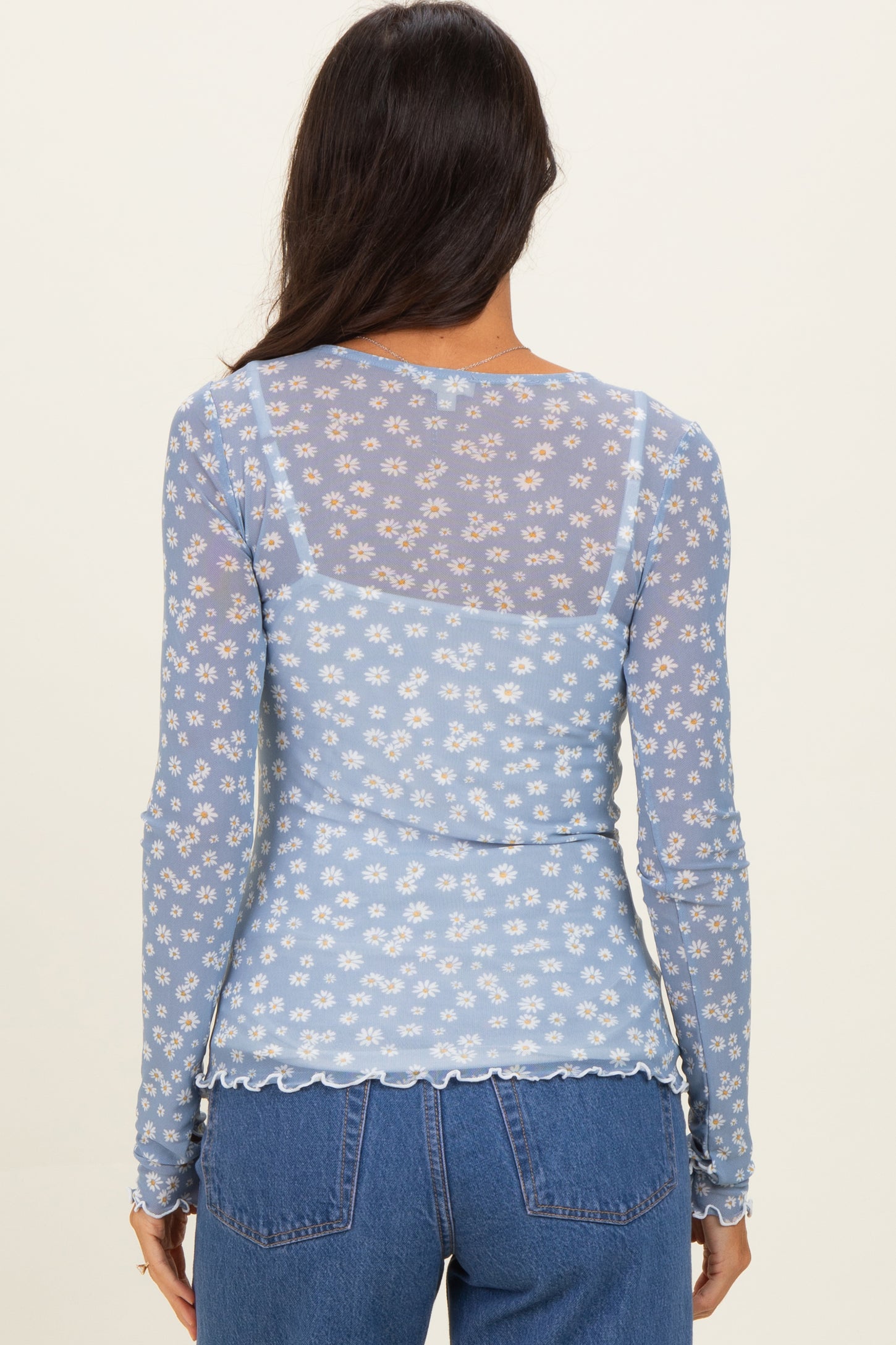 woman wearing a light blue floral sheer long sleeve top with scalloped hem and back design