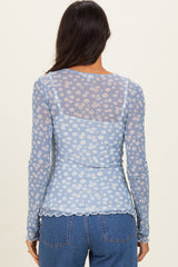 woman wearing a light blue floral sheer long sleeve top with scalloped hem and back design