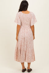 woman wearing a pink floral midi dress with short flutter sleeves and a smocked bodice, seen from the back