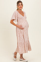 woman wearing a pink floral maternity dress with a smocked bodice and a baby bump visible