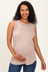 woman wearing a light taupe sleeveless maternity top and holding her baby bump
