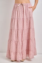 woman wearing a light pink floral tiered maxi skirt with pockets and an elastic waistband