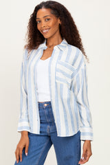woman wearing a light blue striped button-up shirt over a white top with a front pocket and smiling