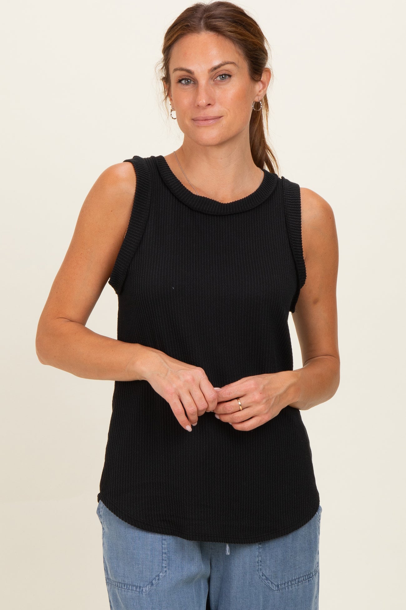 woman wearing a black ribbed sleeveless top with a round neckline and relaxed fit