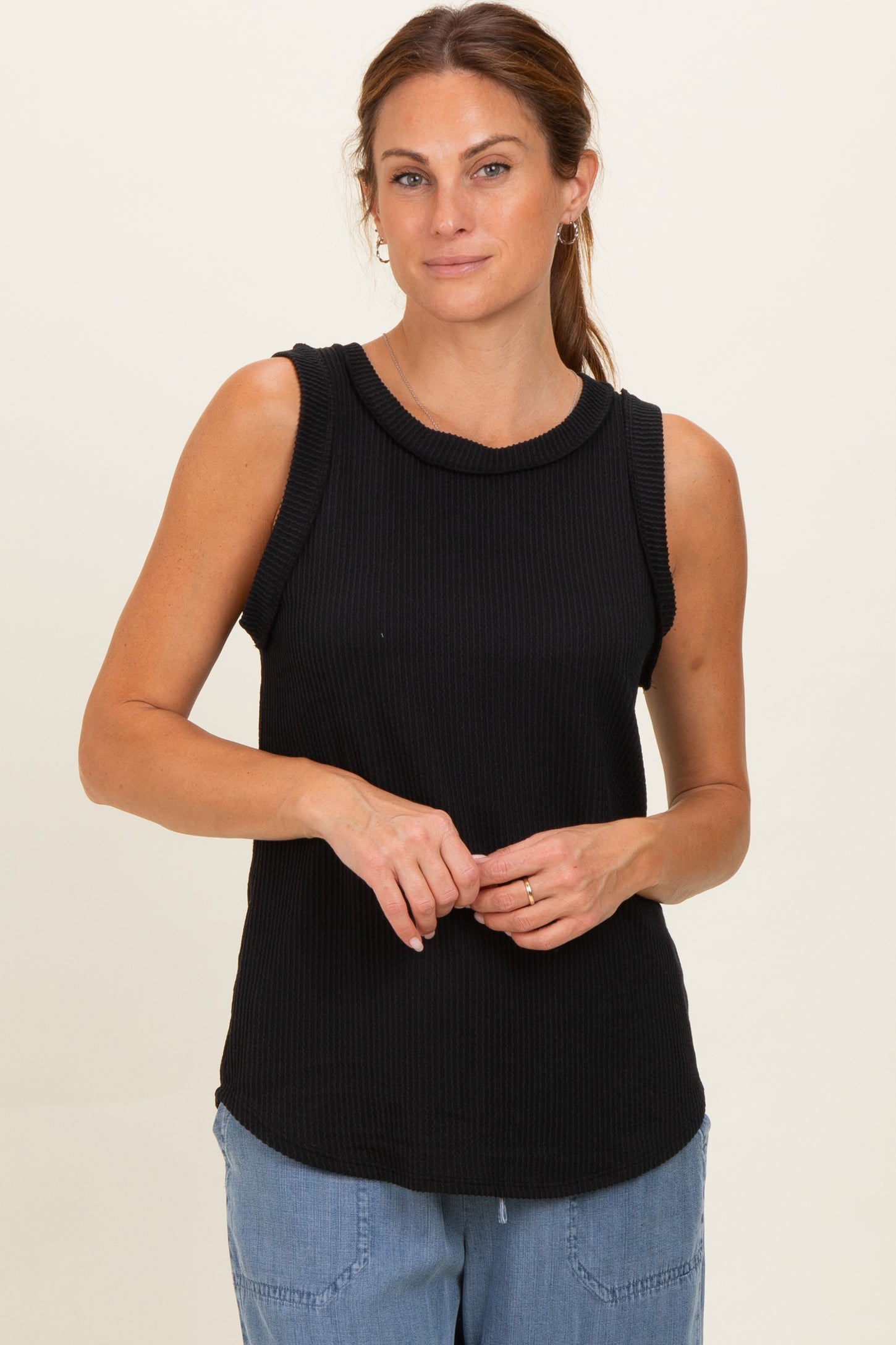woman wearing a black ribbed sleeveless top with a round neckline and relaxed fit