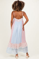 woman wearing a pastel pink and blue color-block maternity dress with floral trim and adjustable spaghetti straps