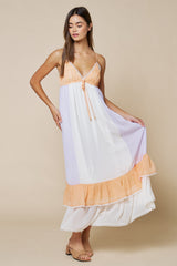 woman wearing a lavender and peach color-blocked maxi dress with a ruffle hem and adjustable spaghetti straps