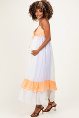 woman wearing a light lavender and coral maternity maxi dress with a tiered skirt and holding her baby bump