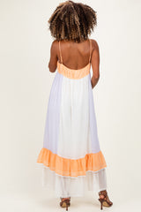 woman wearing a maternity maxi dress with a white and orange colorblock design and adjustable spaghetti straps, showing the back