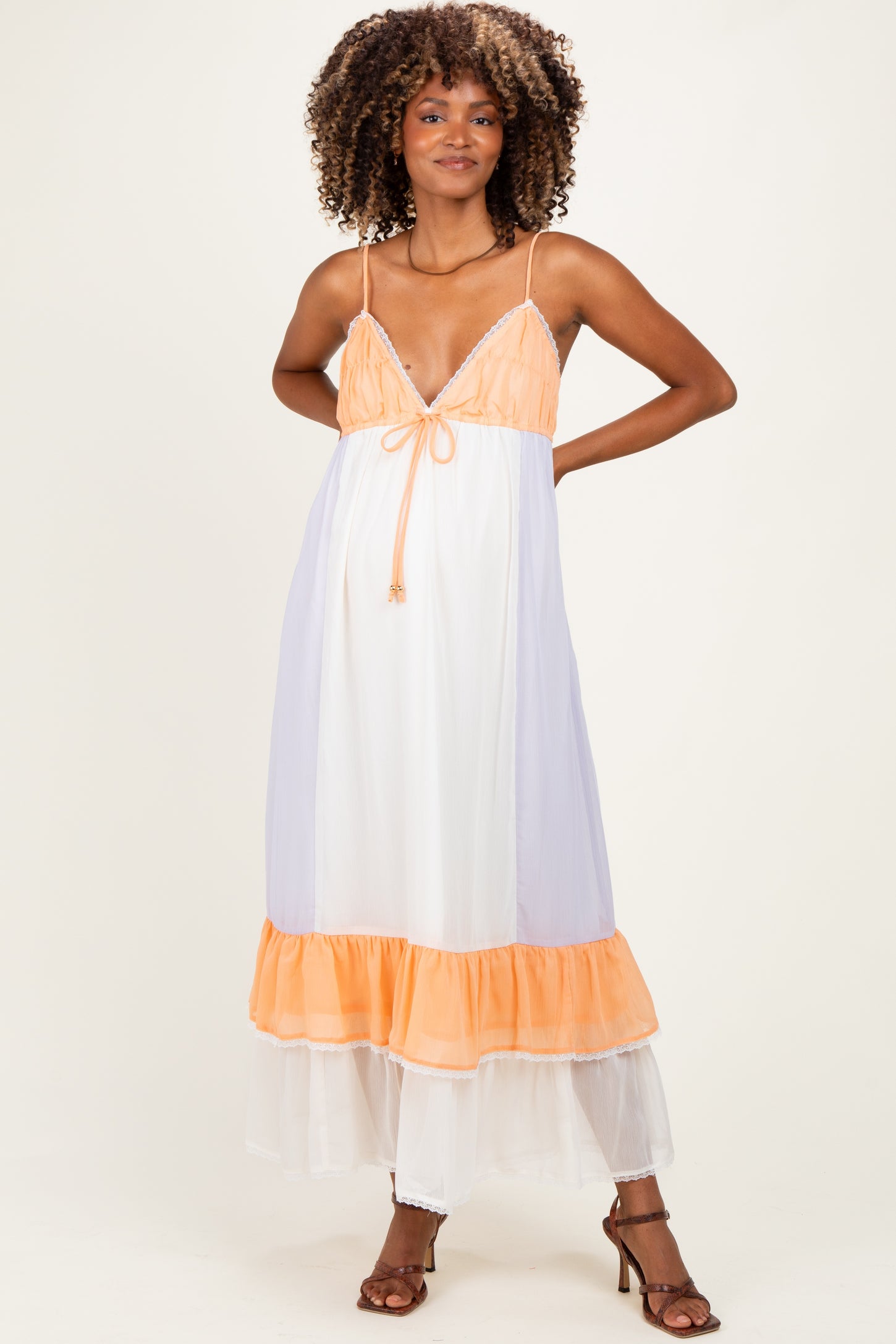 woman wearing a color-blocked maternity dress with orange, white, and lavender colors and a flowy hemline, showing her baby bump