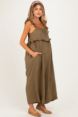 woman wearing an olive green maternity maxi dress with ruffle details and pockets, showing her baby bump