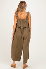 woman wearing a khaki green maternity jumpsuit with ruffle details on the straps and a loose fit
