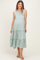 woman wearing a mint green sleeveless maternity dress with a v-neck and tiered skirt, showing a baby bump