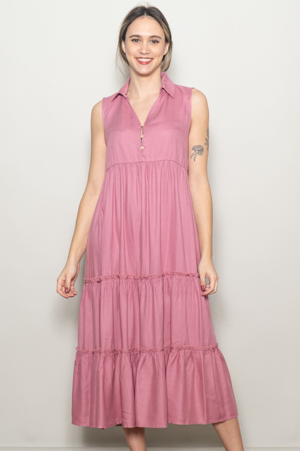 woman wearing a pink sleeveless maxi dress with a collared neckline and tiered ruffle details
