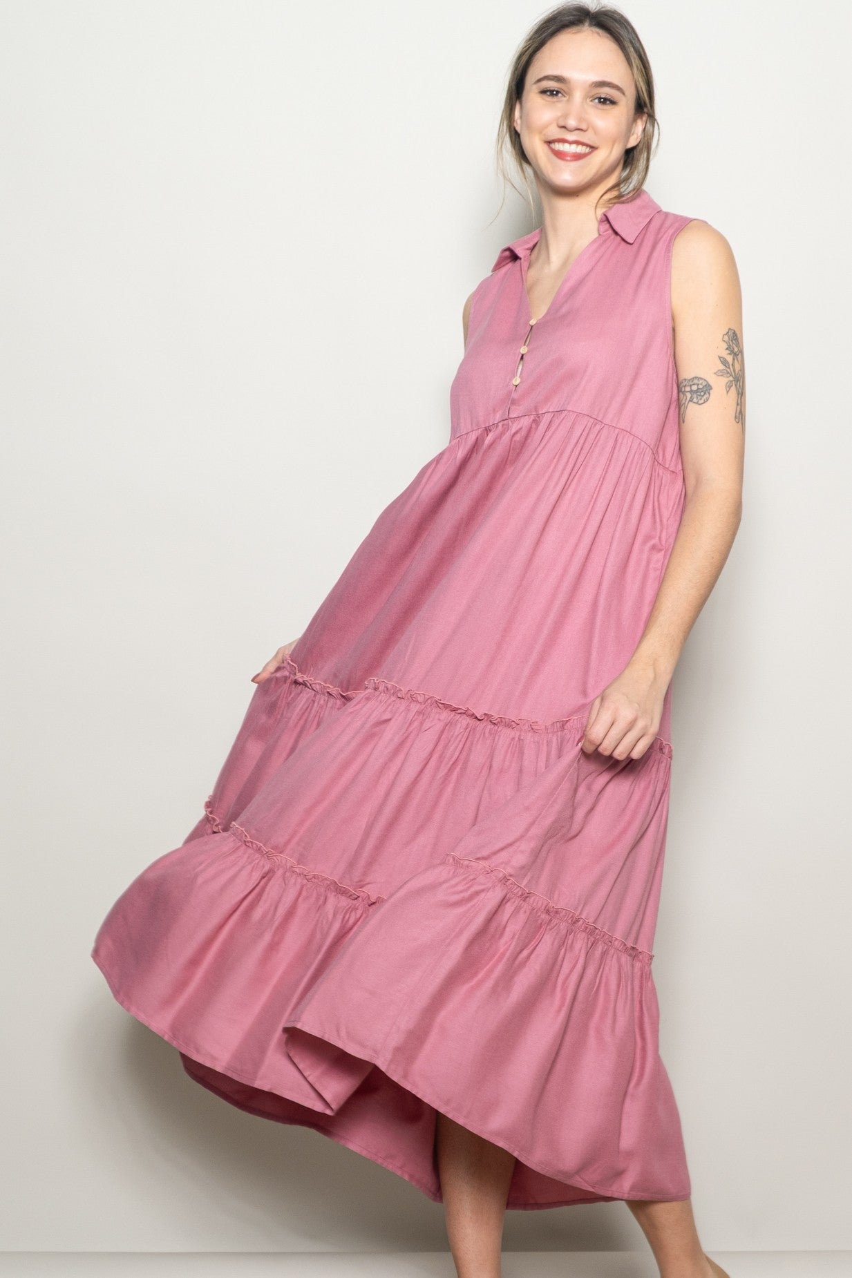 woman wearing a pink sleeveless tiered dress with a collar and button details