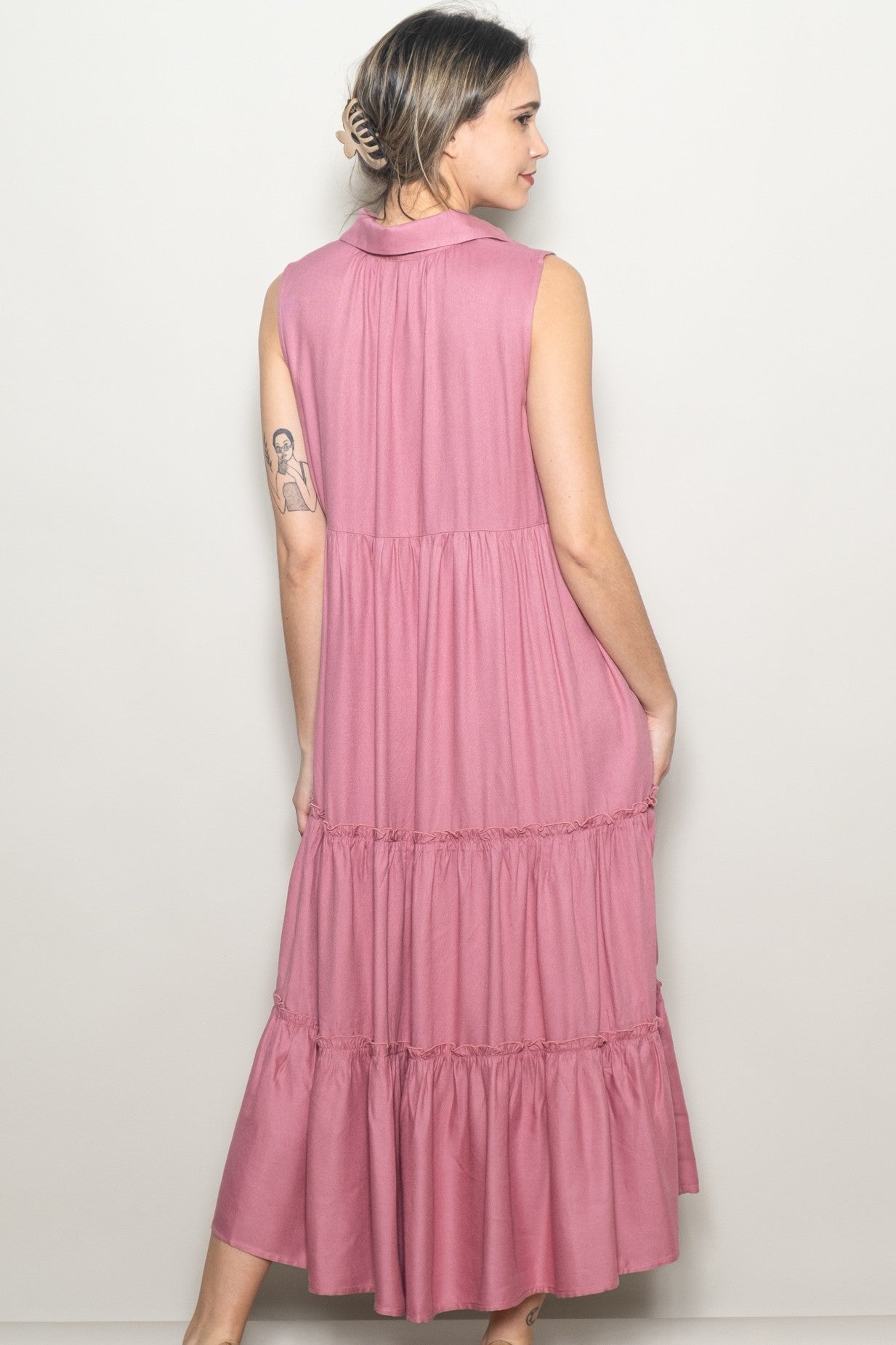 woman wearing a sleeveless pink tiered midi dress with a collar and a flowy silhouette