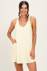 woman wearing a light yellow sleeveless dress with a v-neck and pockets
