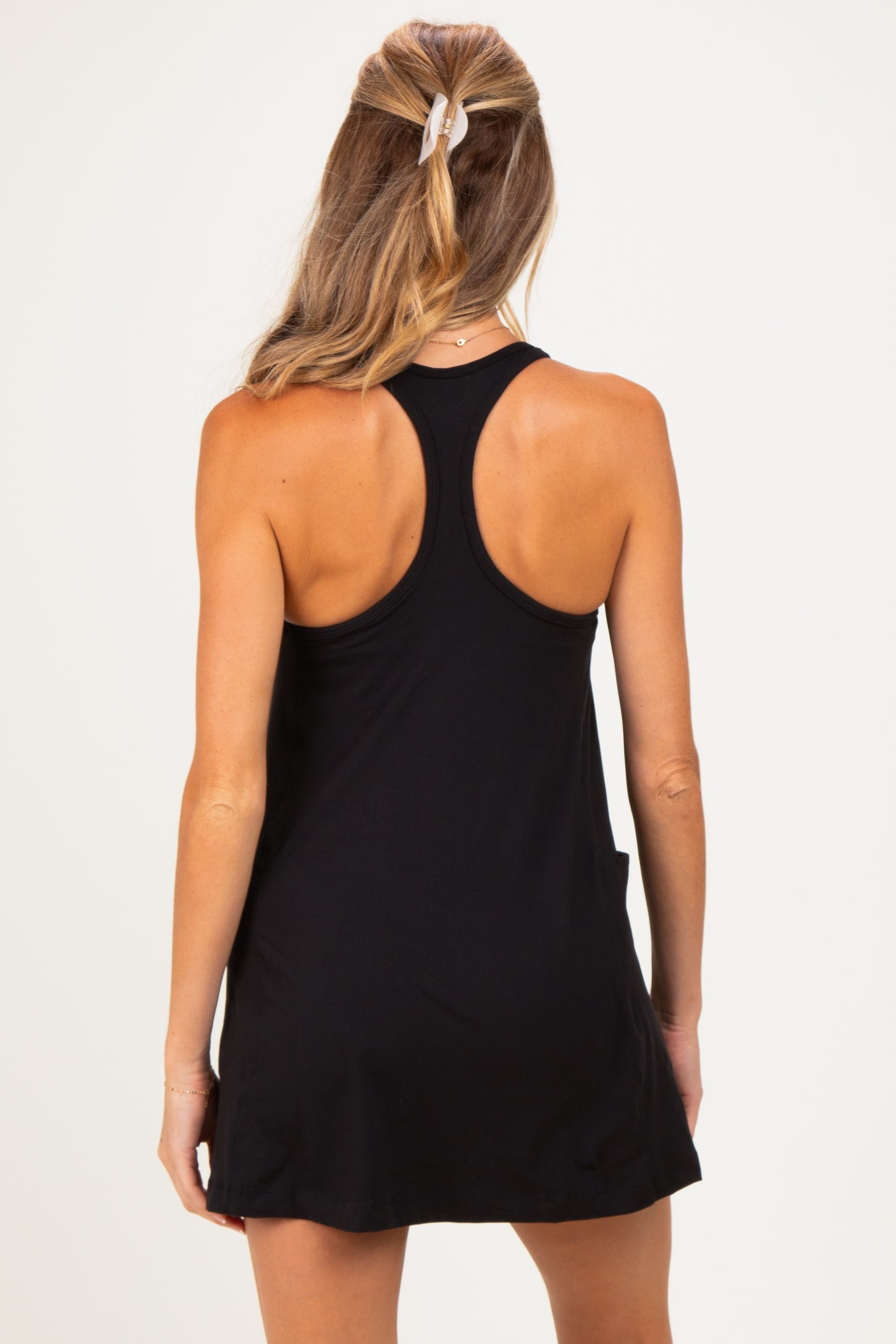 woman wearing a black maternity tank dress, showing a racerback design and a relaxed fit in the back