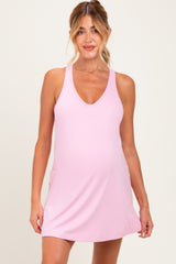 woman wearing a light pink maternity dress with a v-neckline and pockets, showing her baby bump
