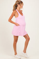 woman wearing a pink maternity dress with pockets and a v-neck, showing her baby bump
