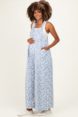woman wearing a blue floral maternity overall dress with pockets and a visible baby bump