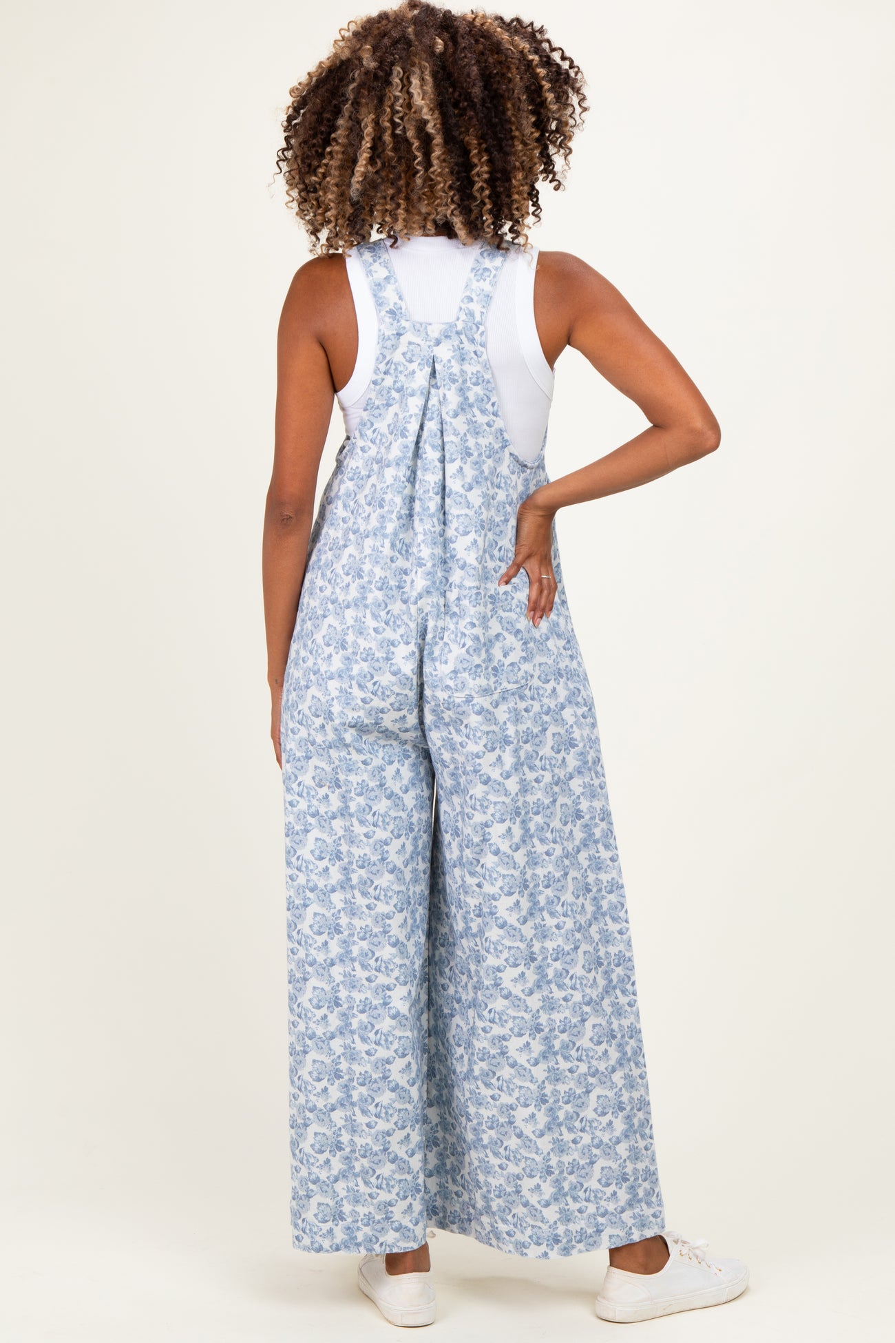woman wearing a blue floral print maternity jumpsuit with wide legs, styled with a white top underneath