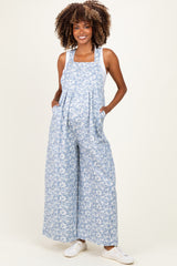 woman wearing a blue floral print maternity overall with wide legs and holding her baby bump