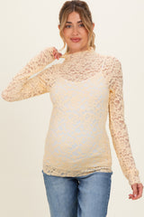 woman wearing a yellow lace long sleeve maternity top and showing her baby bump