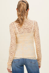 woman wearing a sheer yellow lace maternity top with long sleeves and a fitted silhouette, viewed from the back