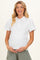 woman wearing a white maternity top with puff sleeves and lace trim, holding her baby bump