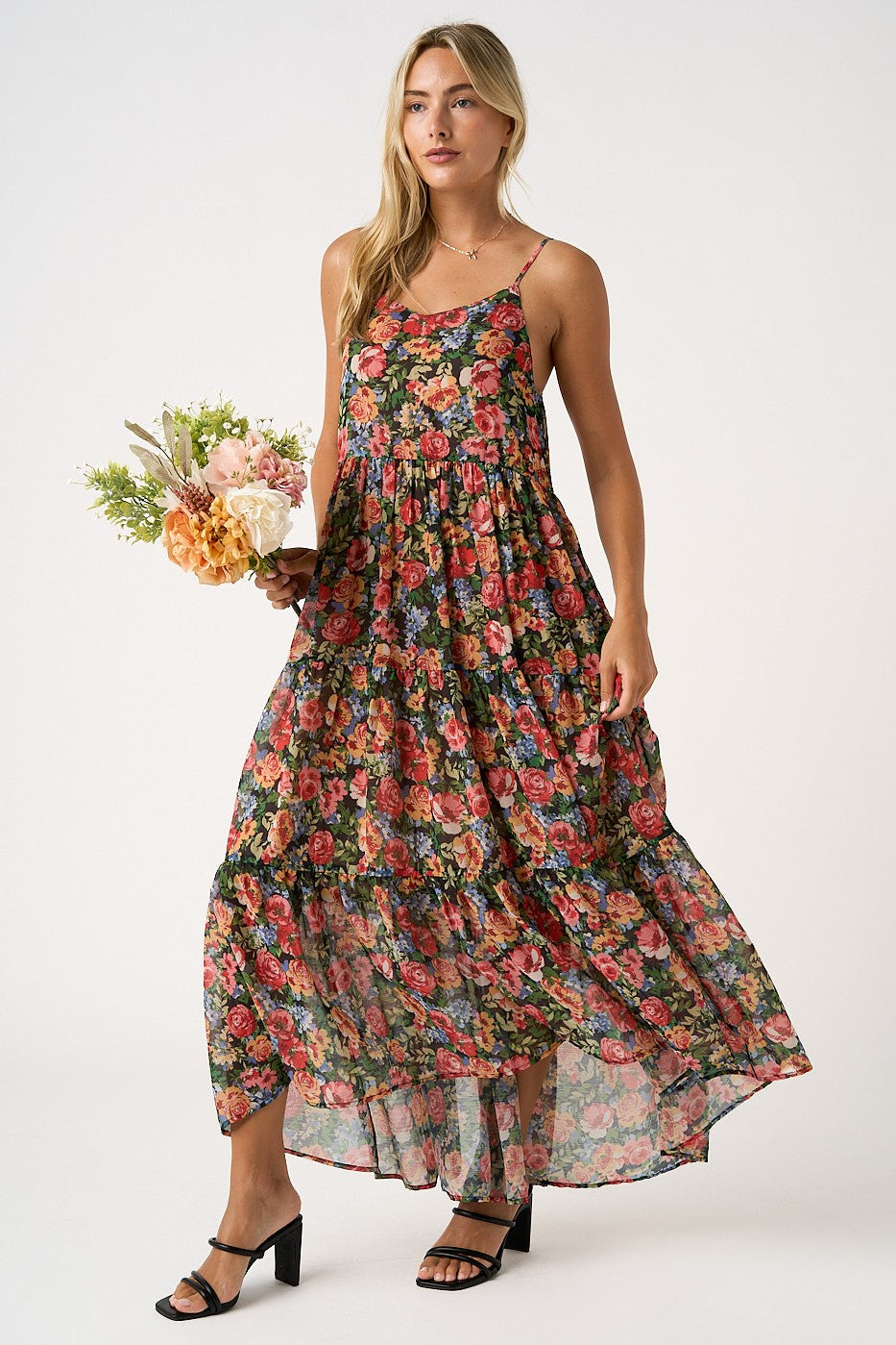 woman wearing a black floral maxi dress with spaghetti straps, holding a bouquet of flowers