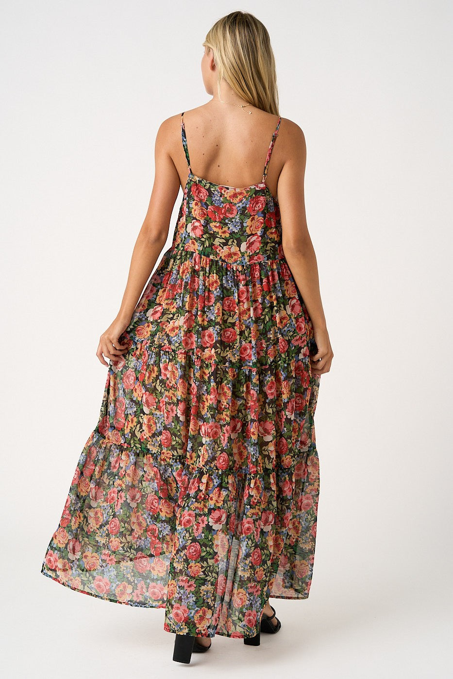woman wearing a floral maxi dress with a tiered design and spaghetti straps, showing the back view