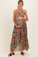 woman wearing a floral maternity maxi dress with a ruffled hem and holding her baby bump