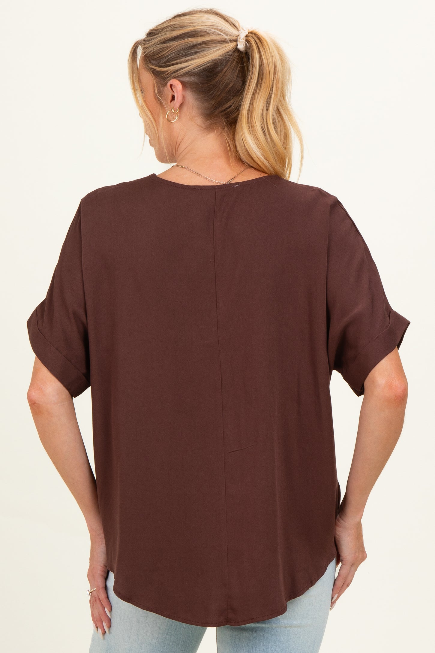 woman wearing a brown short sleeve maternity top, seen from the back