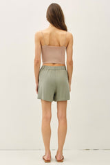 woman wearing a beige cropped tank top and olive green relaxed shorts, seen from the back