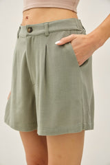 woman wearing light green pleated shorts with side pockets