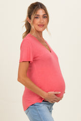 woman wearing a coral v-neck maternity top and holding her baby bump
