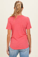 woman wearing a coral short sleeve maternity top, seen from the back with light blue jeans