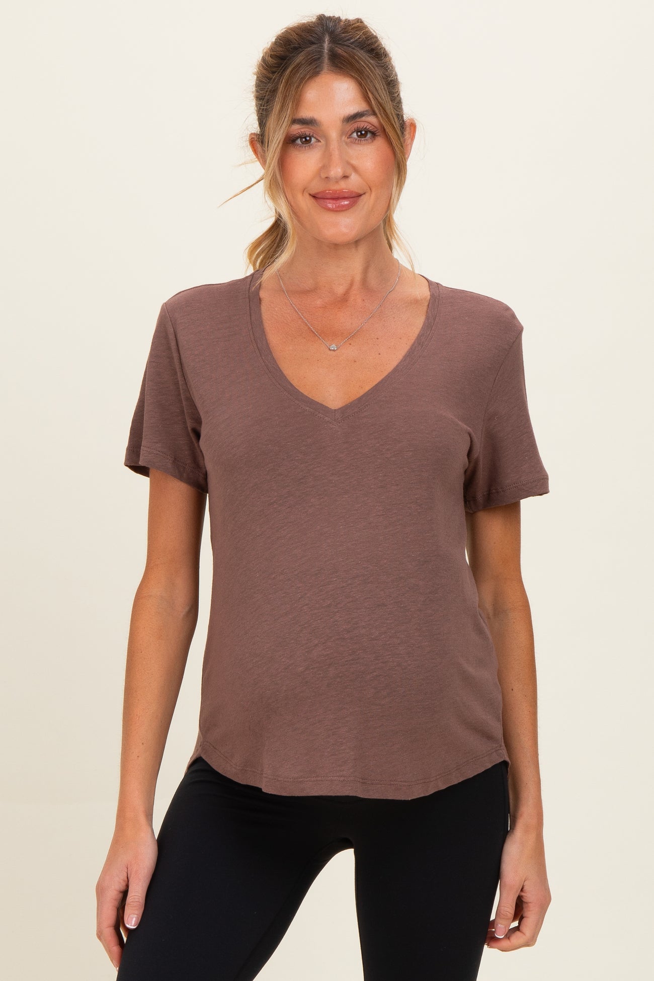 woman wearing a brown short sleeve maternity top with a v-neck and a visible baby bump