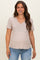woman wearing a light beige maternity top with a v-neckline and short sleeves, showing her baby bump