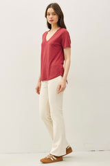 woman wearing a red v-neck t-shirt with short sleeves and cream flared pants, paired with brown sneakers