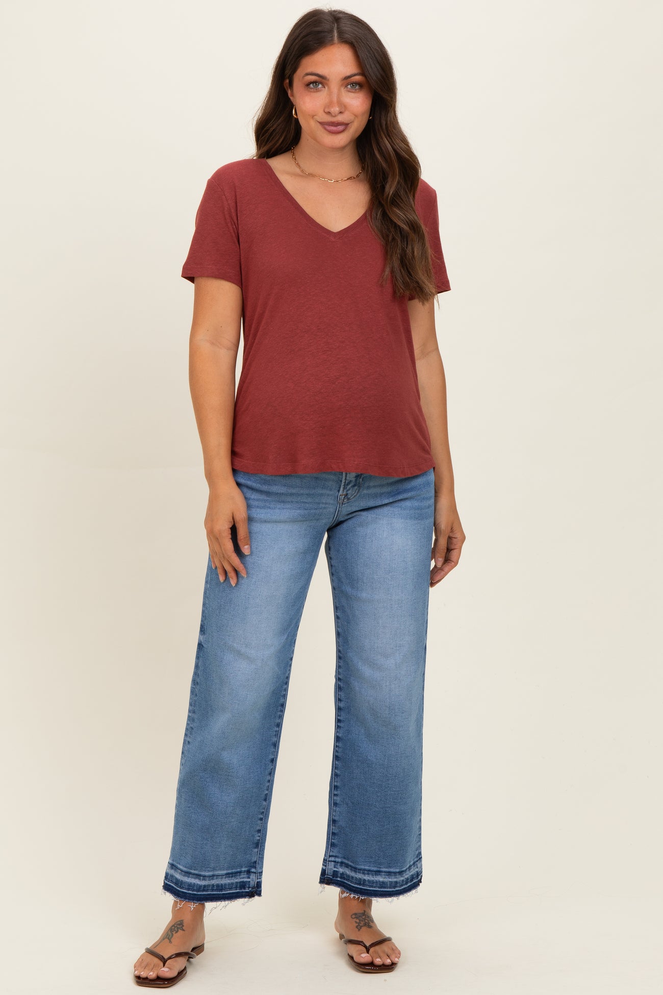 woman wearing a maroon v-neck maternity top with short sleeves and light blue wide-leg maternity jeans