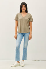 woman wearing a taupe v-neck t-shirt with short sleeves and light blue flared jeans